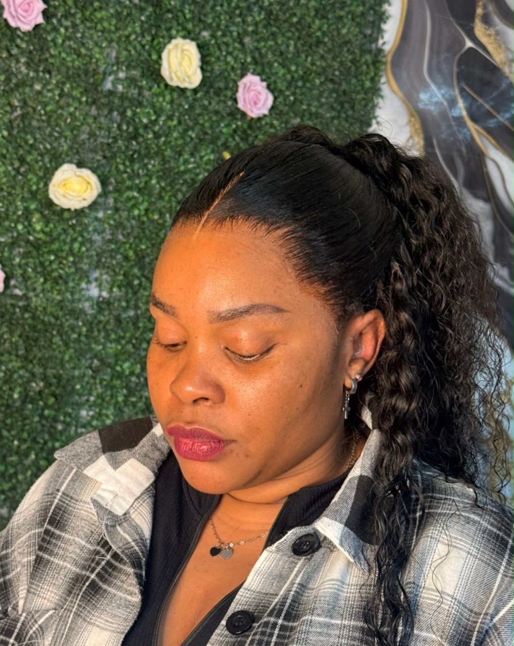 Long curly ponytail installation against floral backdrop
